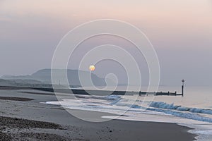 A scenic view of a beautiful sunrise at the beach with some hill in the background