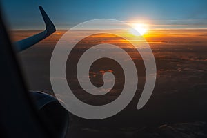 Scenic view of beautiful sunrise, cloudy sky and airplane wing with engine, through window of the aircraft during the flight. Copy