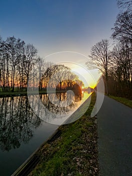 Scenic view of a beautiful sunset over the river in spring against the background of the blue and golden sky, the sun