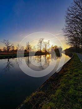 Scenic view of a beautiful sunset over the river in spring against the background of the blue and golden sky, the sun