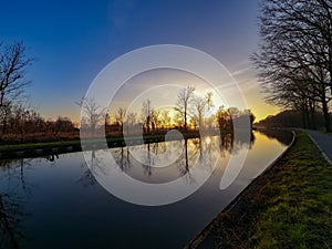 Scenic view of a beautiful sunset over the river in spring against the background of the blue and golden sky, the sun