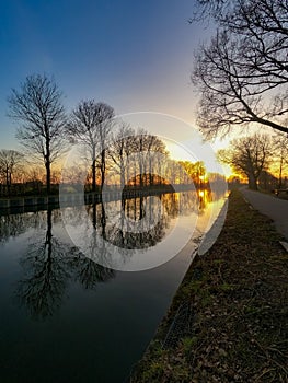 Scenic view of a beautiful sunset over the river in spring against the background of the blue and golden sky, the sun