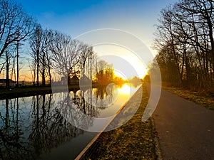 Scenic view of a beautiful sunset over the river in spring against the background of the blue and golden sky, the sun