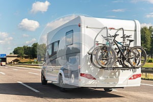 Scenic view big modern white family rv camper van vehicle driving on european highway road against blue sky in summer