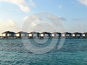 Scenic view of bungalows on a pier on a sea at Maldives at sunset