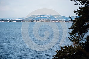 Scenic view of calm cold sea fjord with shore and mountain hills on the background