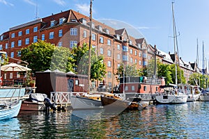 Scenic view Christianshavn Copenhagen canal marina embankment with many boats vessel yachts moored against green trees