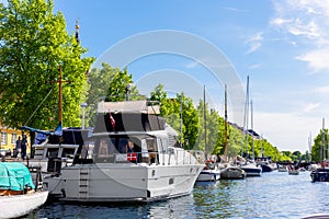 Scenic view Christianshavn Copenhagen canal marina embankment with many boats vessel yachts moored against green trees