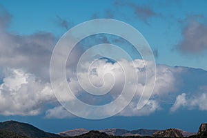 Scenic view on the cloud covered volcano mountain peak Pico del Teide on Tenerife seen from La Gomera, Canary Islands