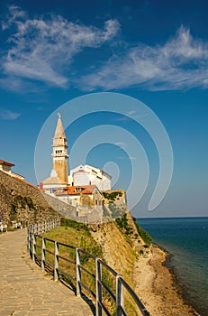 Scenic view of coastline of Adriatic sea with alley along Piran old city walls and cathedral on background, Slovenia