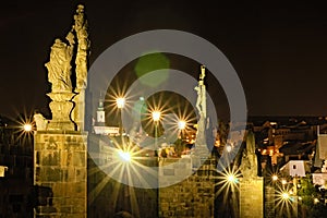 Scenic view of famous Charles Bridge with historic statues, buildings and landmarks of old town at the background at summer night.