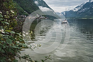 Scenic view of famous Hallstatt lakeside and pleasure boat reflecting in Hallstattersee lake in the Austrian Alps