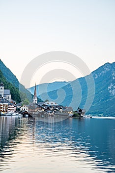 Scenic view of famous Hallstatt lakeside town reflecting in Hallstattersee lake in the Austrian Alps on a sunny day in summer,