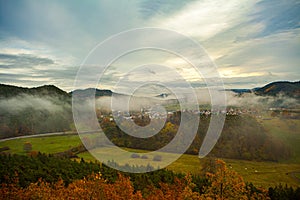 a scenic view of a forest with mountains in the background and trees in the foreground with yellow and green leaves