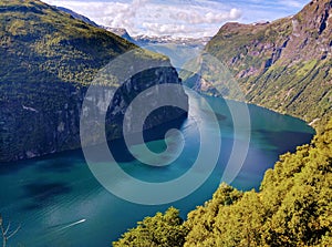 A scenic view of the Geiranger fjord in Norway taken from the Gjerdefossen viewpoint on a sunny day.