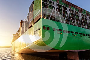 Scenic view giant cargo container ship loading Hamburg city port harbour against seaport cranes warm evening sunset