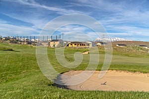 Scenic view of golf course and homes against blue sky and clouds on a sunny day