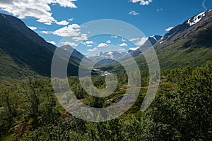 Scenic view on green valleys and mountain sides with snowy peaks along the scenic Sognefjellet road
