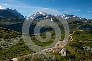 Scenic view on green valleys and mountain sides with snowy peaks along the scenic Sognefjellet road