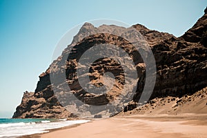 Scenic view of gui gui beach in gran canaria island in spain with spectacular mountains landscape and clear blue sky and sandy photo