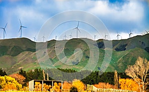 Scenic view of hay bales , wind turbines and mountains against sky