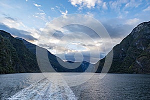 Scenic view of huge rocky mountains in cloudy sky background surrounded by the lake