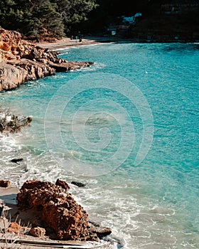Scenic view of Ibiza beach with fishermen's huts, blue water and rocks on Beach Cala Saladeta photo