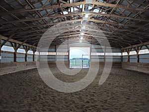 Scenic view of an interior of a barn with a sandy floor illuminated by light bulbs