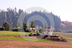 Scenic view of an isolated gazebo standing on a side of a lawn in a farming fields