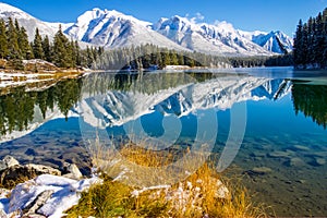 A scenic view of Johnson Lake in late fall with mountain peaks covered in snow.