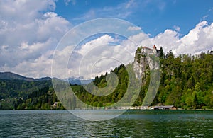 Scenic view of Lake Bled with castle on the rock and mountains covered by clouds on background at springtime, Slovenia