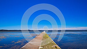 Scenic view of a long jetty in Tuggerah lake under a clear blue sky photo