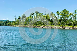 Scenic view of lush, green tropical shoreline under clear blue sky