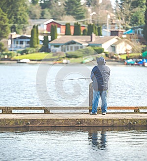 Scenic view of a man fishing on a pier in a big lake in the park.