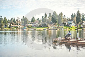 Scenic view of a man fishing on a pier in a big lake in the park.