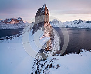 Scenic View from Mount Hesten on Iconic Mountain Segla at dawn in winter with snow in front of colorful sky and mountain range