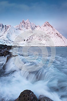 Scenic View from Mount Hesten on Iconic Mountain Segla at dawn in winter with snow in front of colorful sky and mountain range