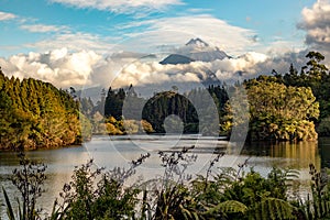 Scenic view on Mount Taranaki Mount Egmont in beautiful clouds over a forest and a lake