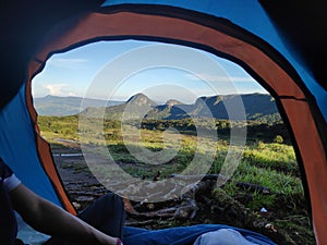 Scenic view of a mountain range covered with mist in morning thorough a camping tent