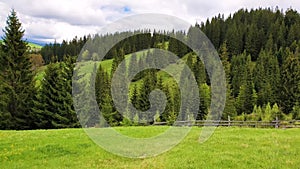 Scenic view of mountains nature and a old village on the hills with wooden cabins. Sunny spring day with green grass, flowering me