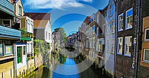 Scenic view on narrow dutch water canal with residential houses on both sides against blue summer sky - Dordrecht, Netherlands