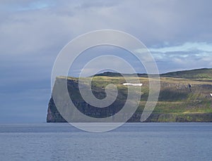 Scenic view from ocean on beautiful snow patched cliff in west f photo