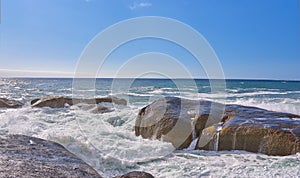 Scenic view of ocean waves and water washing over boulders and rocks in Camps Bay, Cape Town, South Africa. Empty