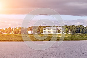 Scenic view of a old manor house by a river. Sun flare