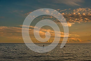 Scenic view of people puddling in the sea at sunset