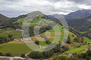 Scenic view of Pyrenees mountains with village in valley, France. Landscape of Camino de Santiago. Colorful meadows in valley.