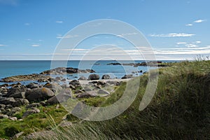 Scenic view of rocks and green plants on Brusand Beach, Norway on a sunny summer day photo