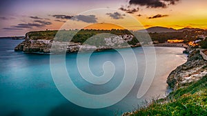 Scenic view of rocky shoreline and blue sea at sunset. Cala Romantica, Mallorca, Spain.