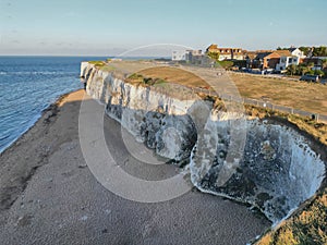 Scenic view of a rugged cliff jutting out over the water with a beach and houses. Broadstairs, UK.