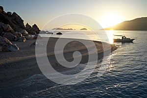 Scenic view of sea with rocks at beach during sunset.